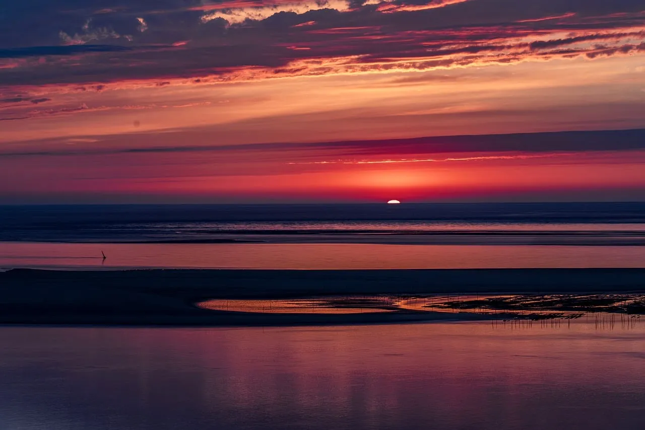 Dramatic Coastal Sunset: Fiery Hues Over Tranquil Waters