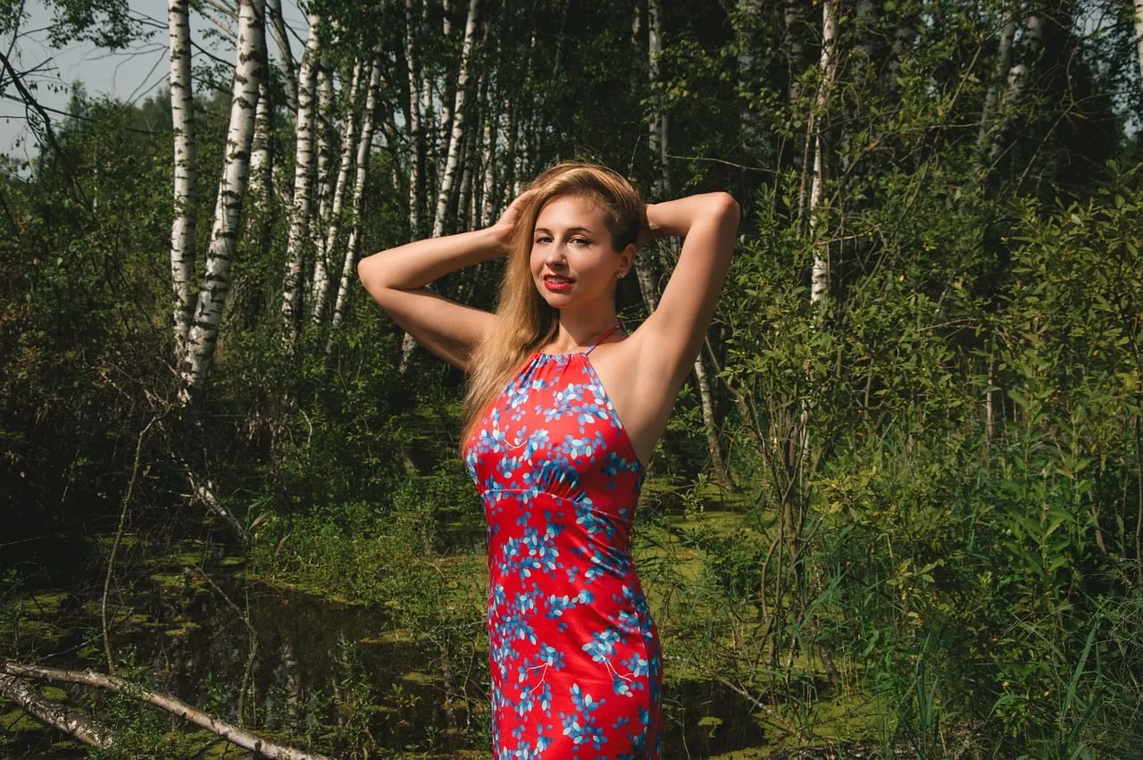 Stunning Blonde in Red Floral Dress Amidst Lush Forest