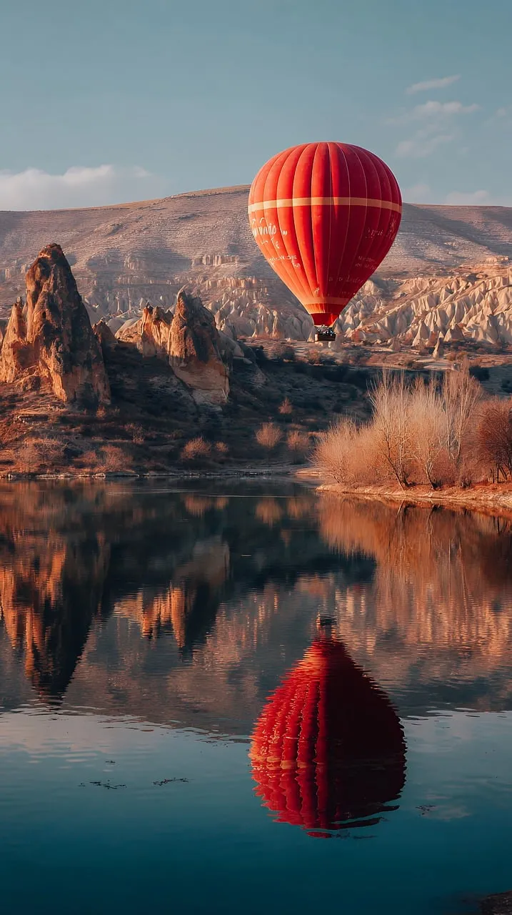 Breathtaking Red Hot Air Balloon Soaring Over Mountainous Reflections