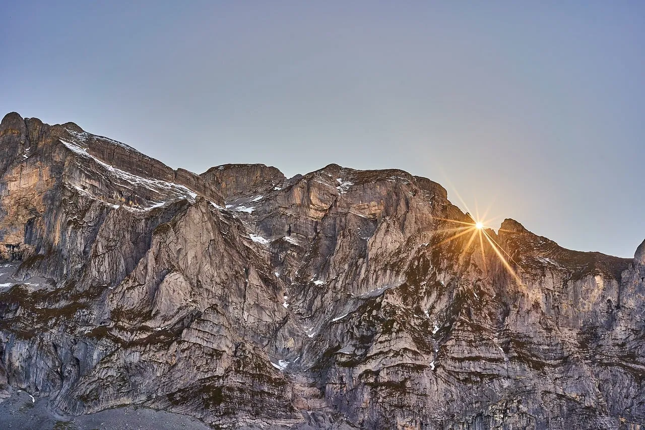Breathtaking Alpine Sunrise: Golden Sunburst over Craggy Peaks