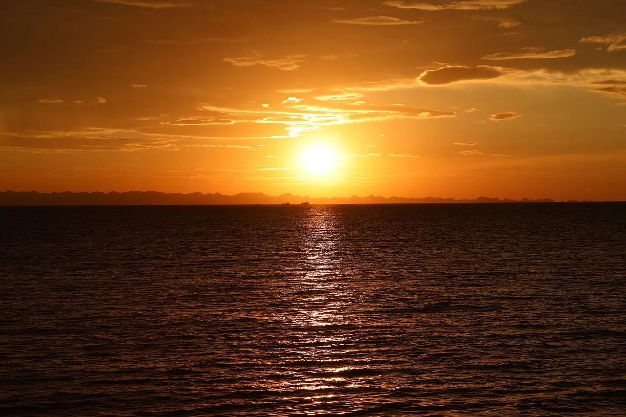 Breathtaking Golden Hour: Serene Ocean Sunset Over Distant Mountains