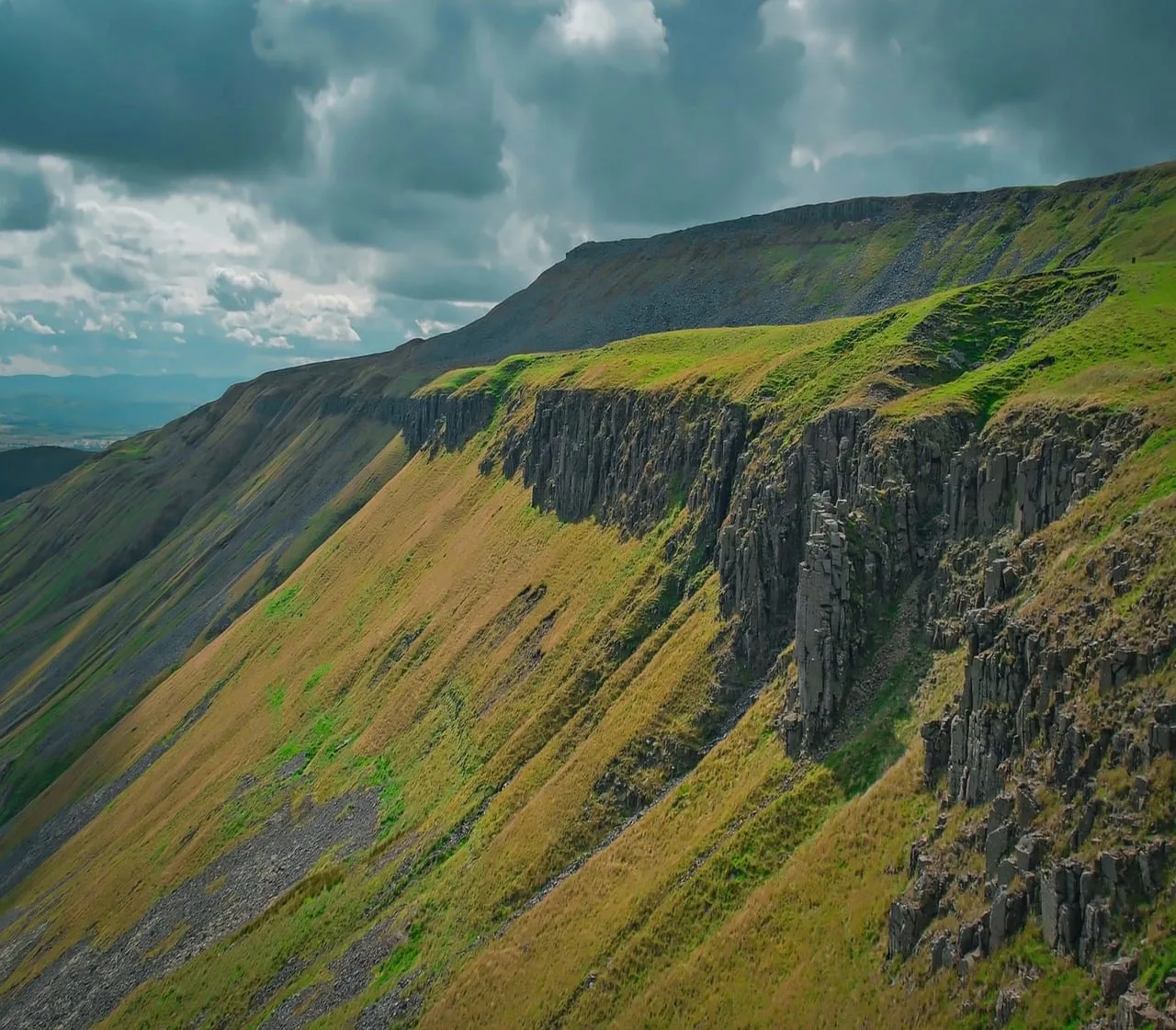 Dramatic Alpine Majesty: Lush Cliffs Under Dynamic Skies