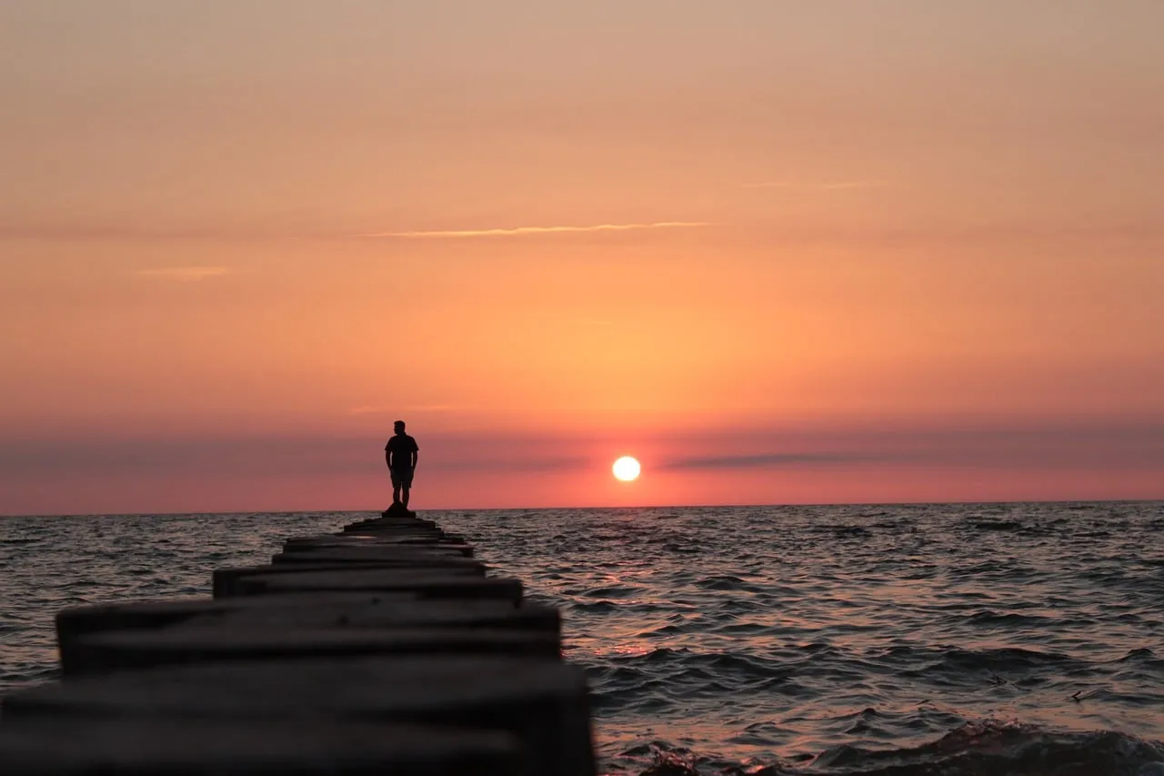 Breathtaking Sunset Silhouette: Lone Figure on a Pier