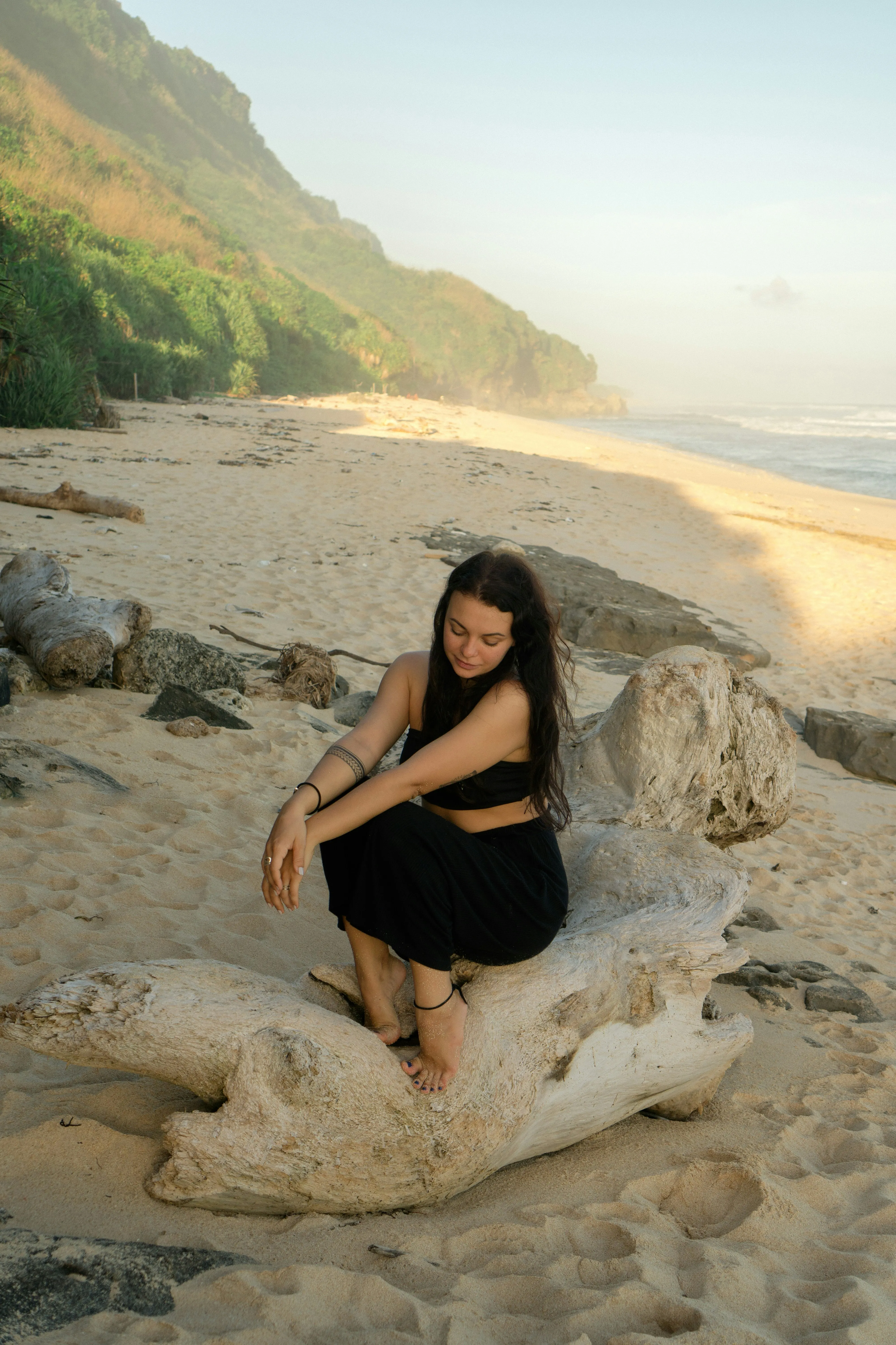 Serene Moment: Woman on Driftwood at Golden Beach