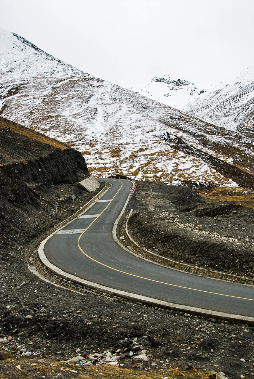 Dramatic Alpine Drive: Winding Road Through Karola Glacier's Snowy Peaks