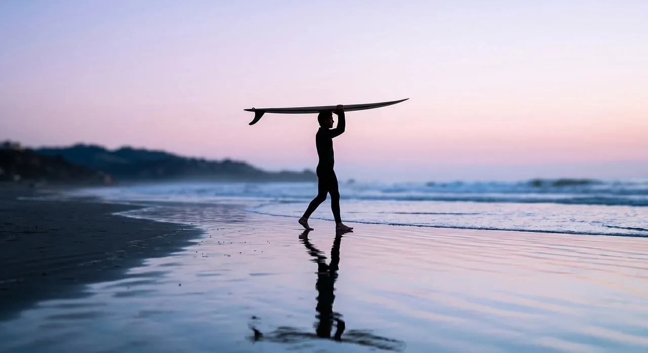Serene Sunset Surfer: Silhouette on a Reflective Beach