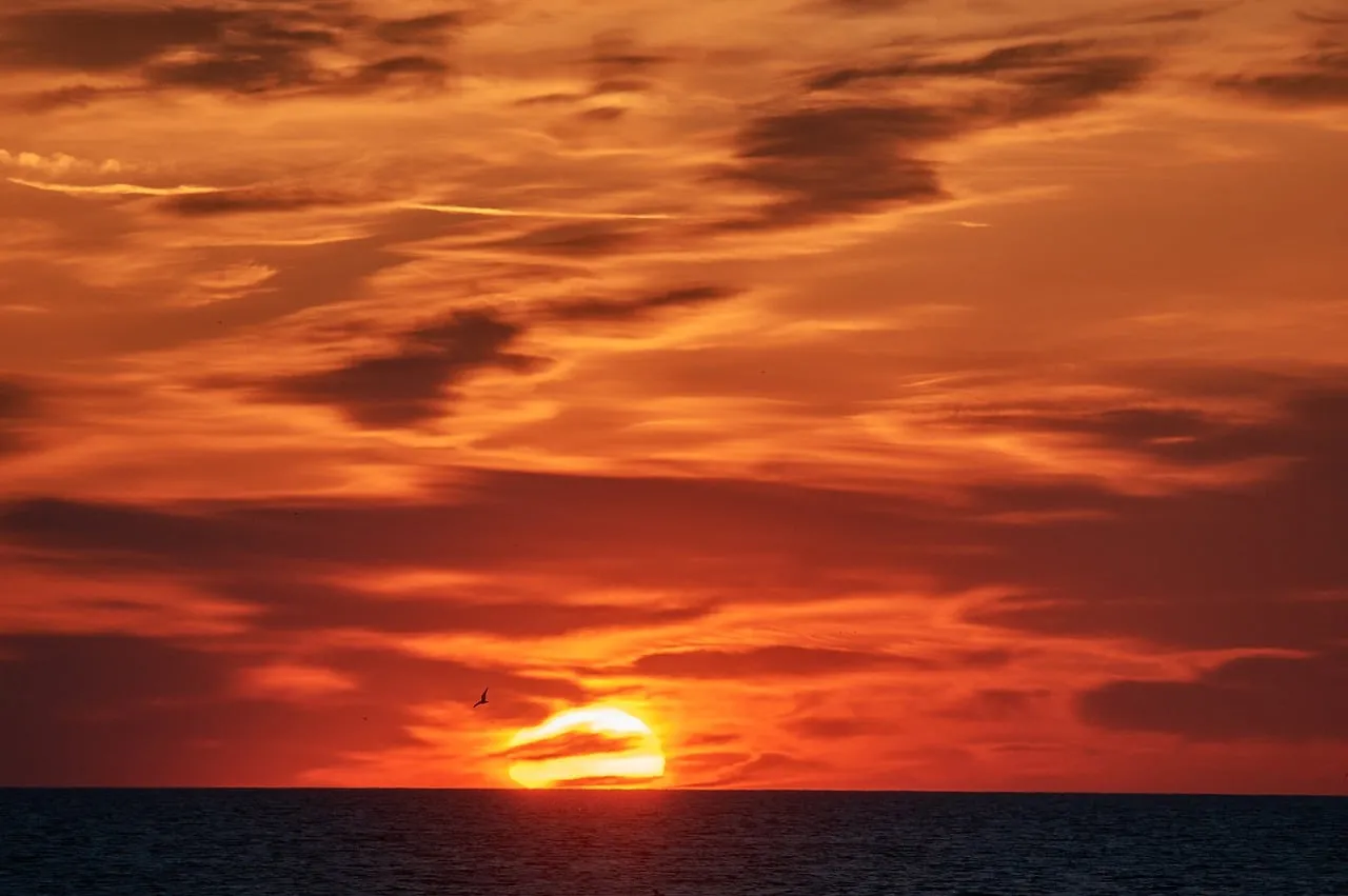 Fiery Sunset Over Calm Sea: A Breath-taking Evening Sky