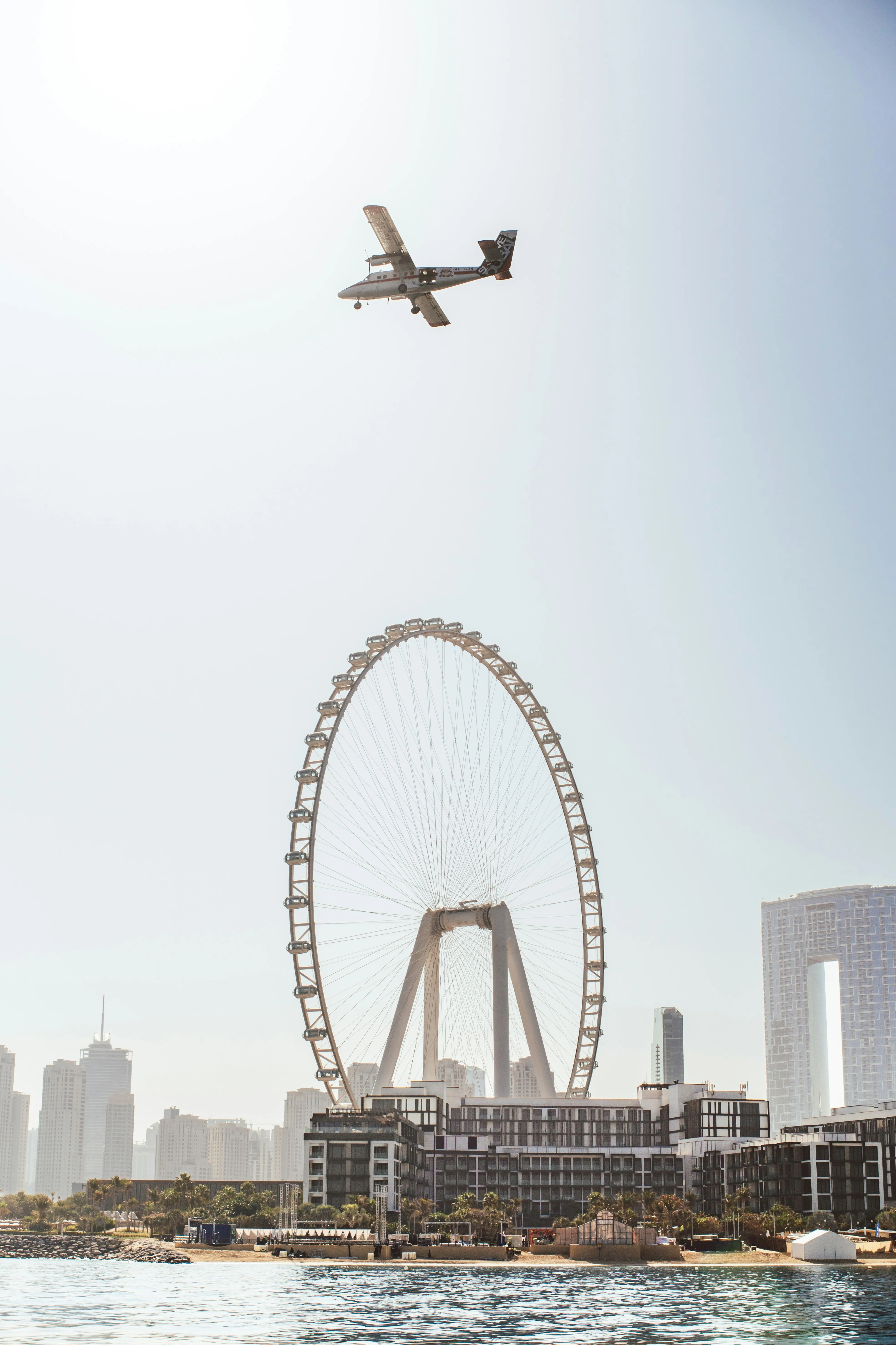 Dramatic Sky: Airplane Soars Over Iconic Ferris Wheel
