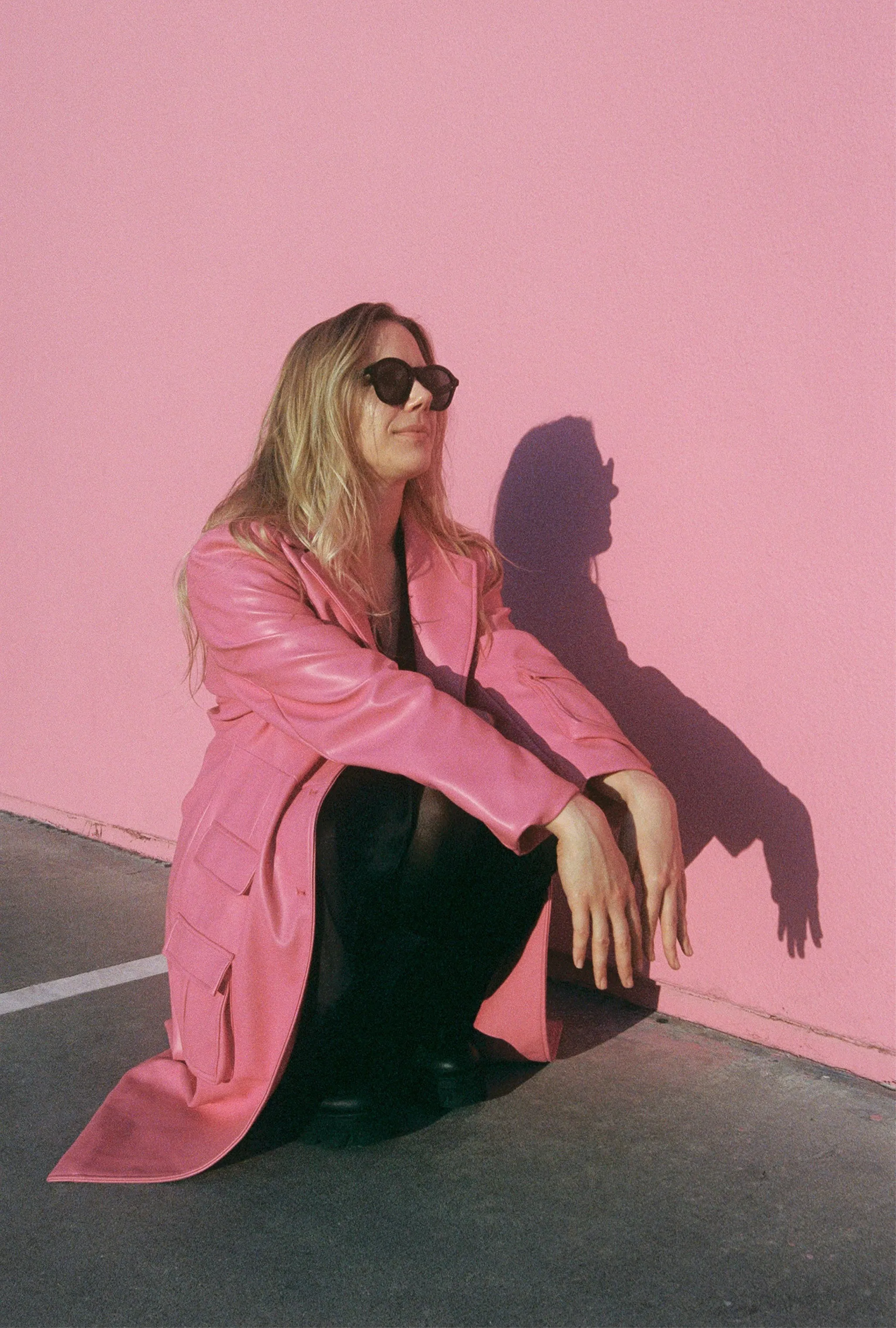Chic Pink & Shadow: Woman's Edgy Style Against Vibrant Wall