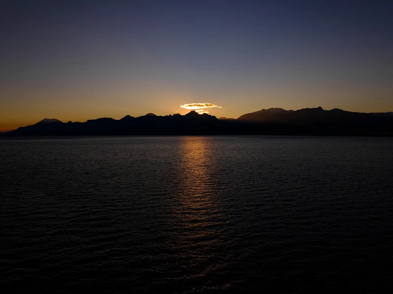 Dramatic Sunset Over Sea and Silhouetted Mountains
