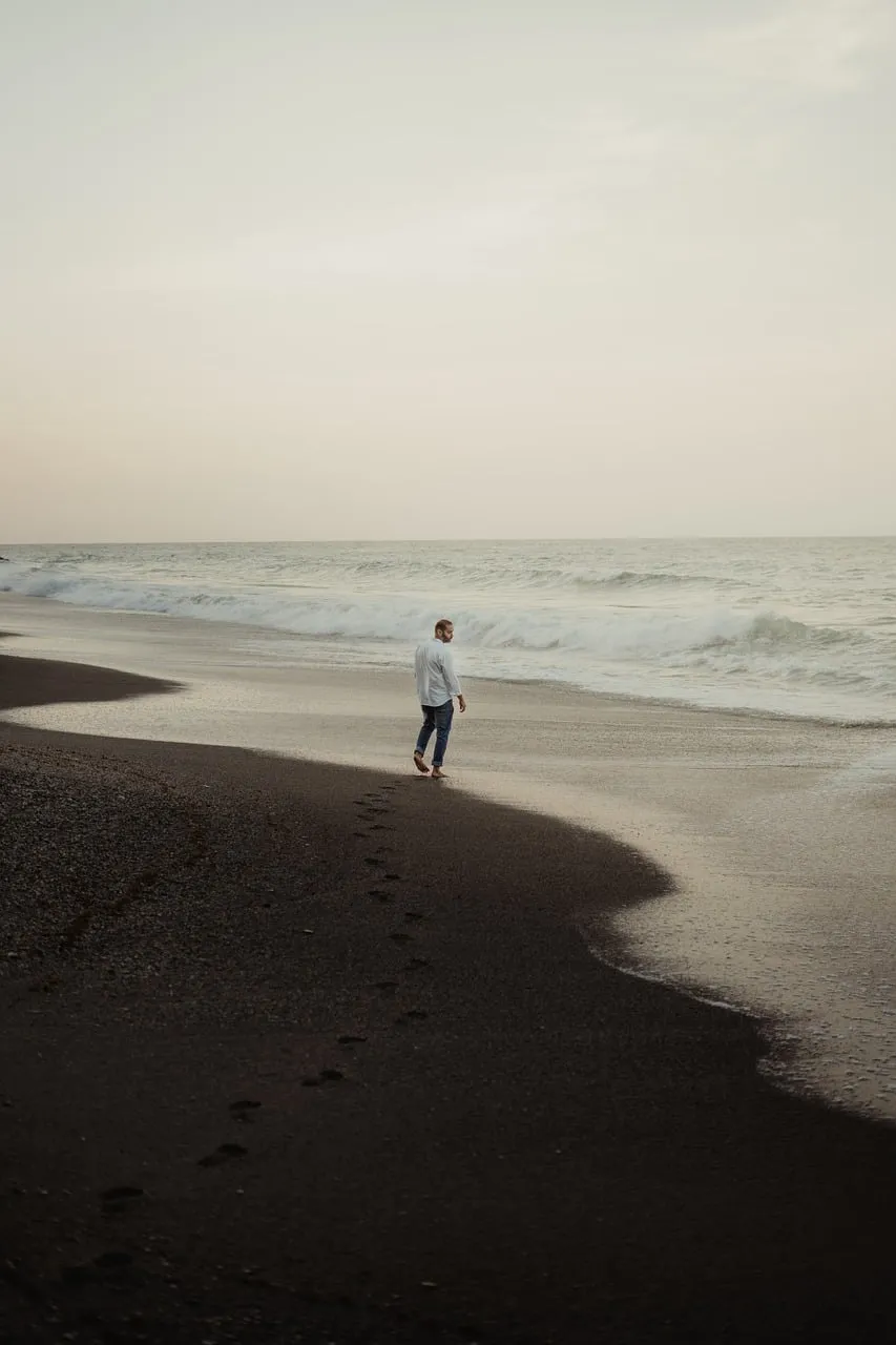 Serene Solitude: Man Walking on a Quiet Sunset Beach