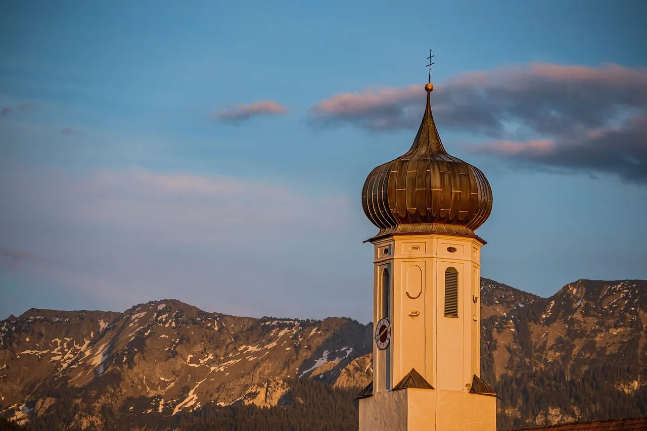 Enchanting Bavarian Sunset: Church Spire Against Alpine Glow