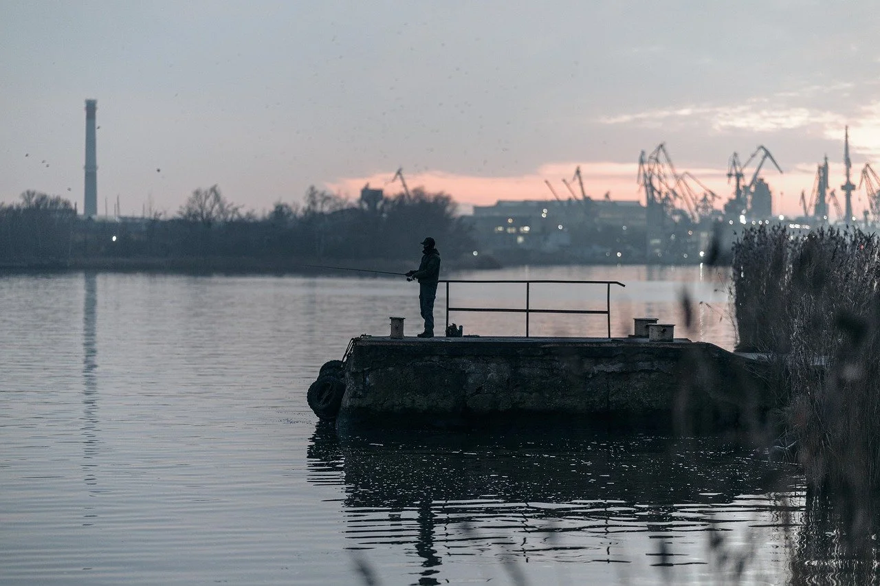 Serene Sunset Silhouette: A Fisherman's Tranquil Harbor View