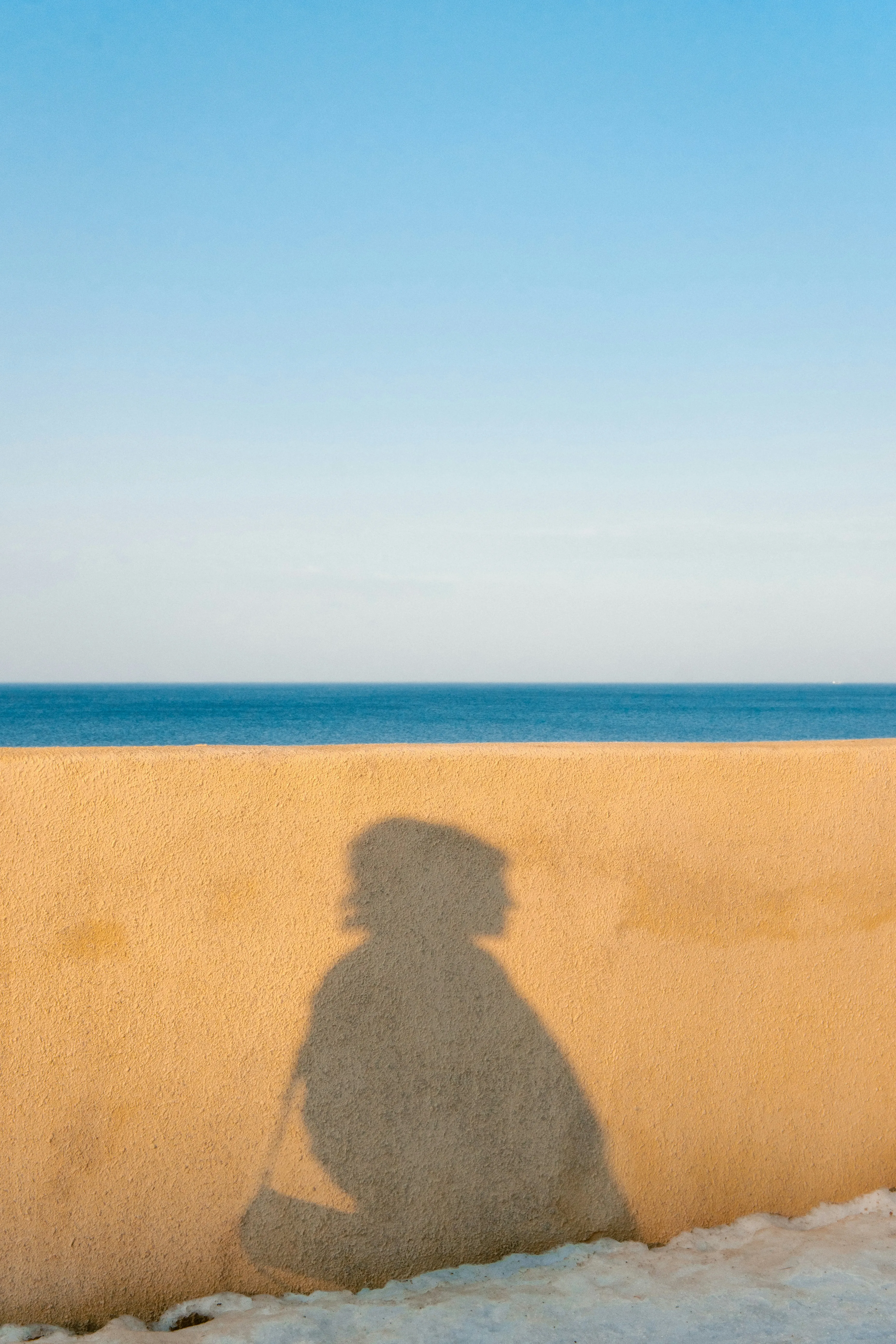 Striking Silhouette: Person's Shadow on a Coastal Wall
