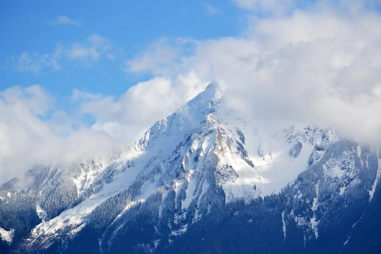Majestic Snow-Capped Peak Amidst Whispering Clouds