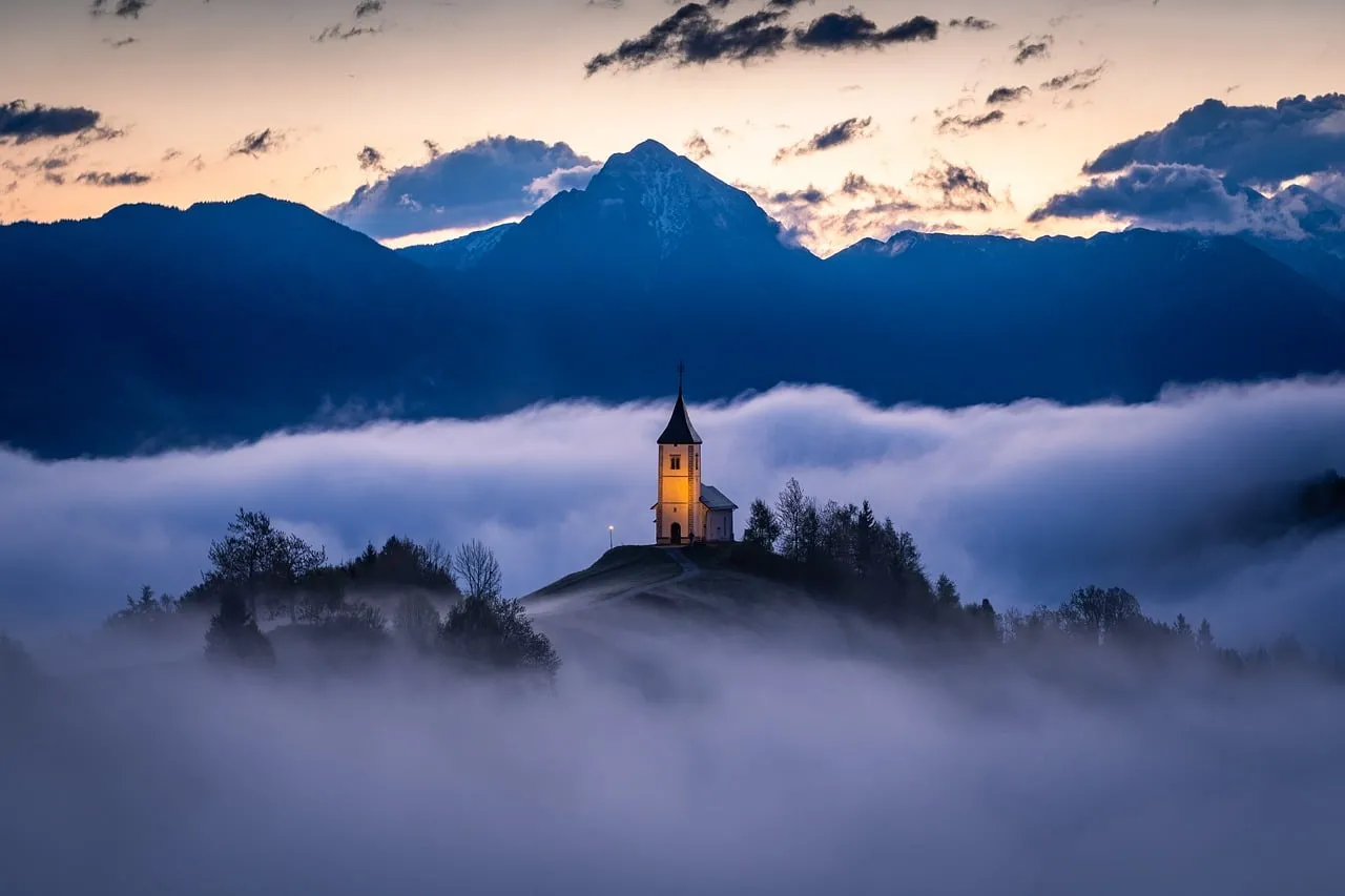 Mystical Slovenian Chapel Emerging from a Foggy Dawn