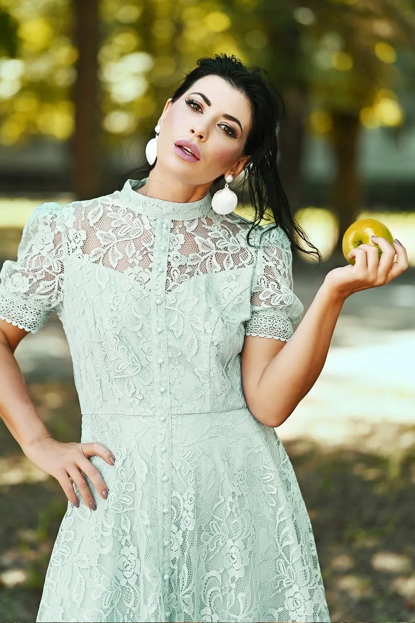 Charming Woman in Lace Dress Holding Apple in Nature's Embrace