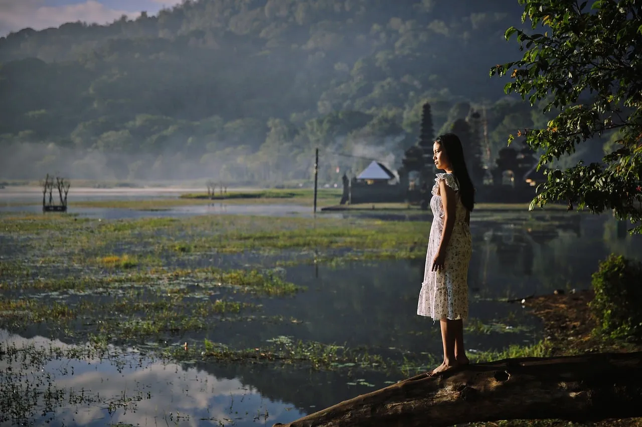 Serene Dawn: Woman Reflecting by an Ancient Indonesian Lake