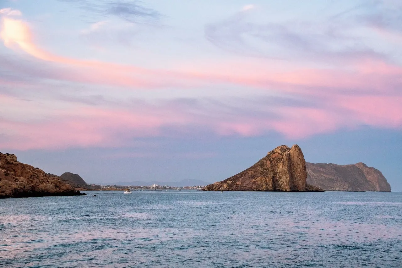 Breathtaking Coastal Sunset: Serene Sea and Dramatic Rock Formations