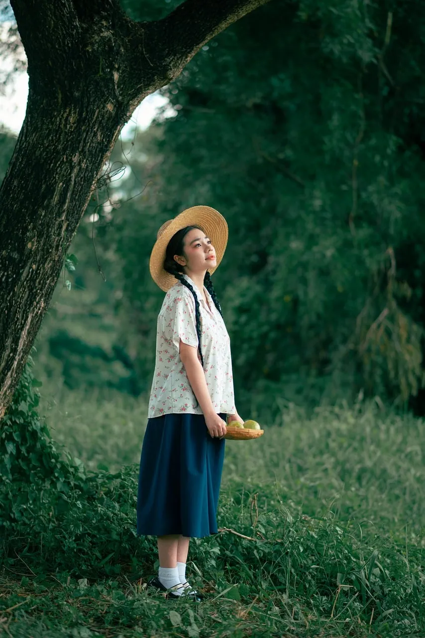 Serene Summer Day: Woman in Hat Beneath Guava Tree