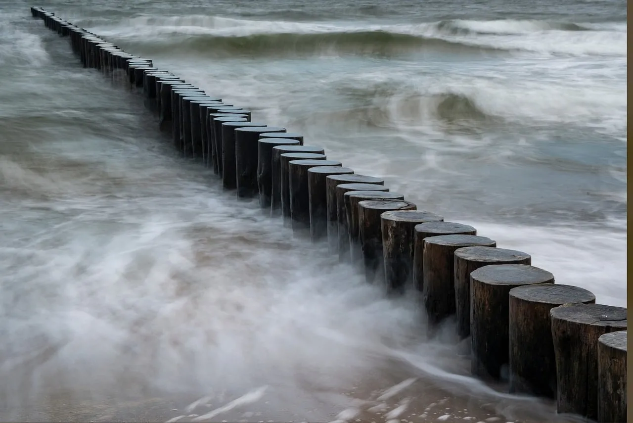 Dramatic Coastal Erosion: Ocean Waves and Weathered Wooden Pilings