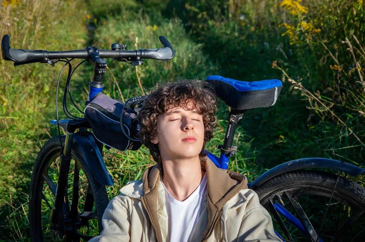 Serene Sunlight Escape: Young Man Relaxing with His Bicycle in Nature