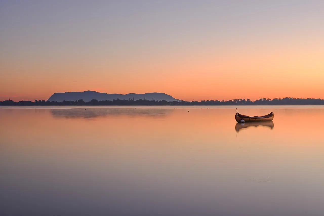 Serene Quebec Sunrise: Lonely Canoe on Tranquil Lake