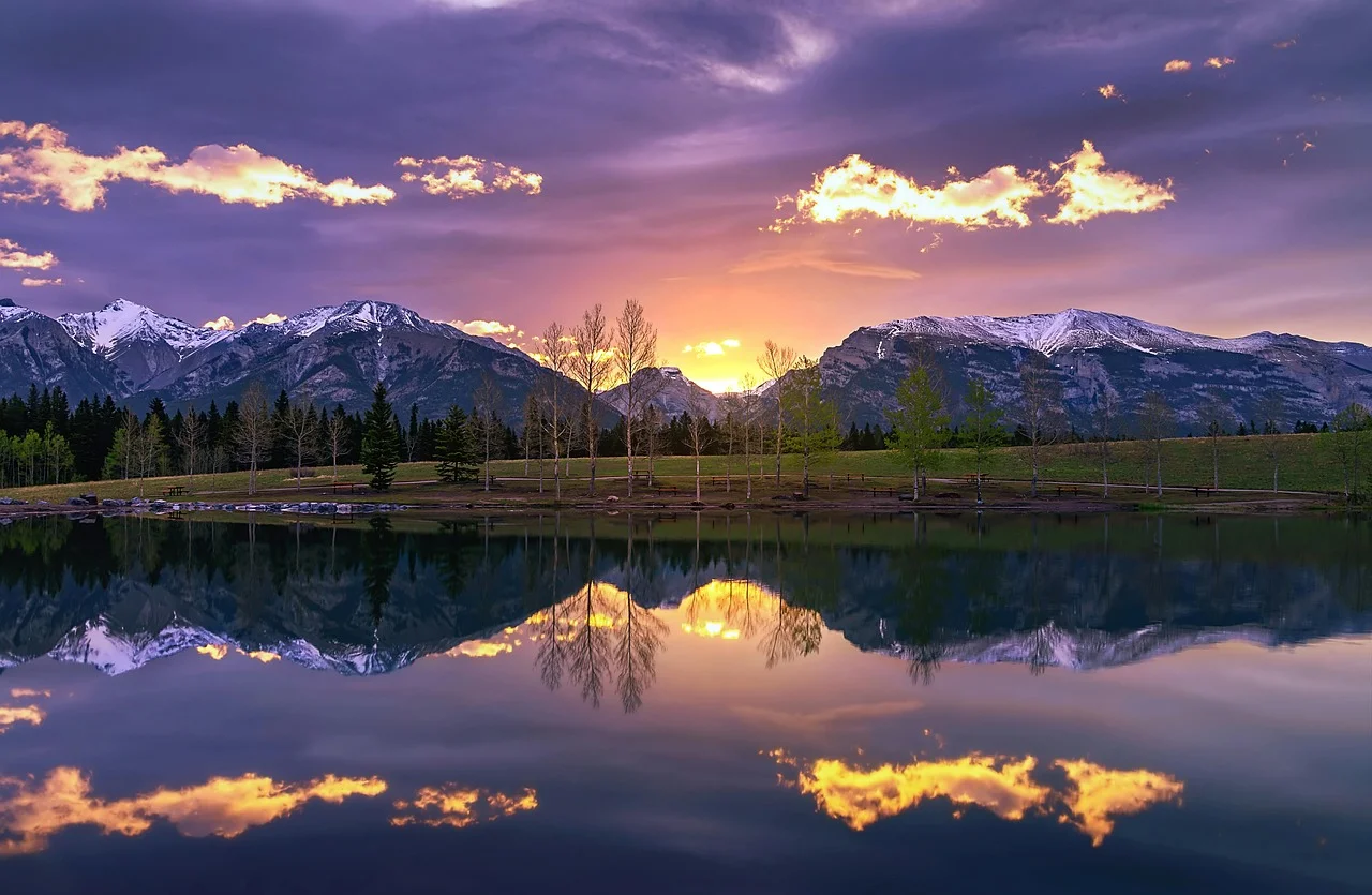 Breathtaking Sunset Over Majestic Mountains Reflected in Calm Waters