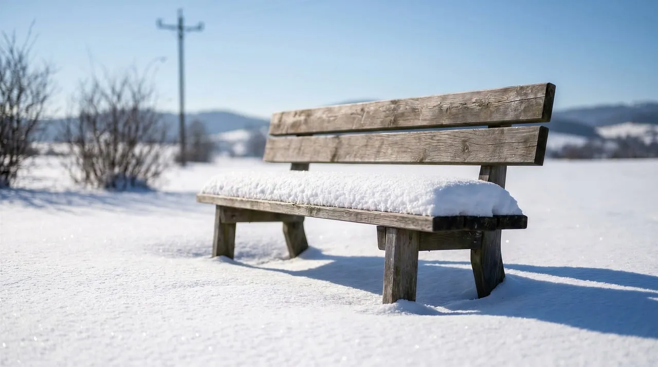 Serene Snow-Covered Bench in Winter Sunlight