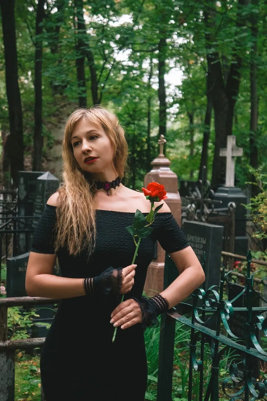 Gothic Elegance: Woman with Red Rose in a Mysterious Cemetery