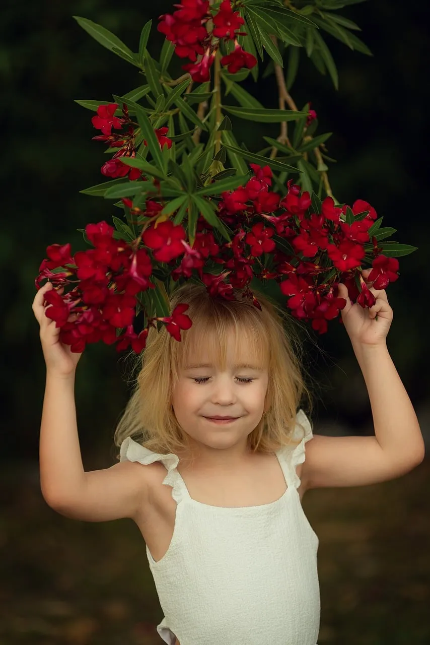 Charming Child Embracing Nature's Red Oleander Blooms