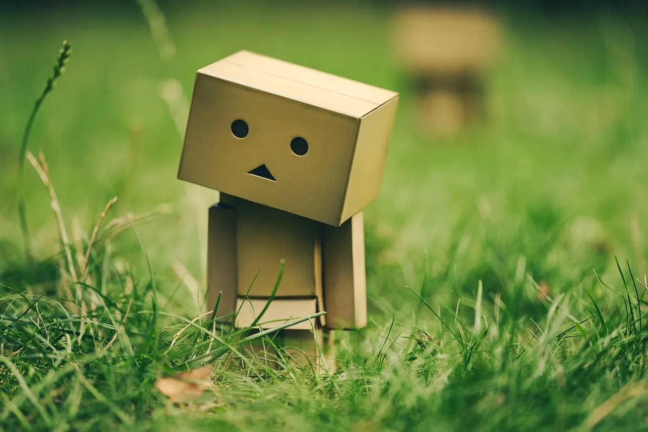 Charming Cardboard Robot Embraces Nature in Lush Green Grass