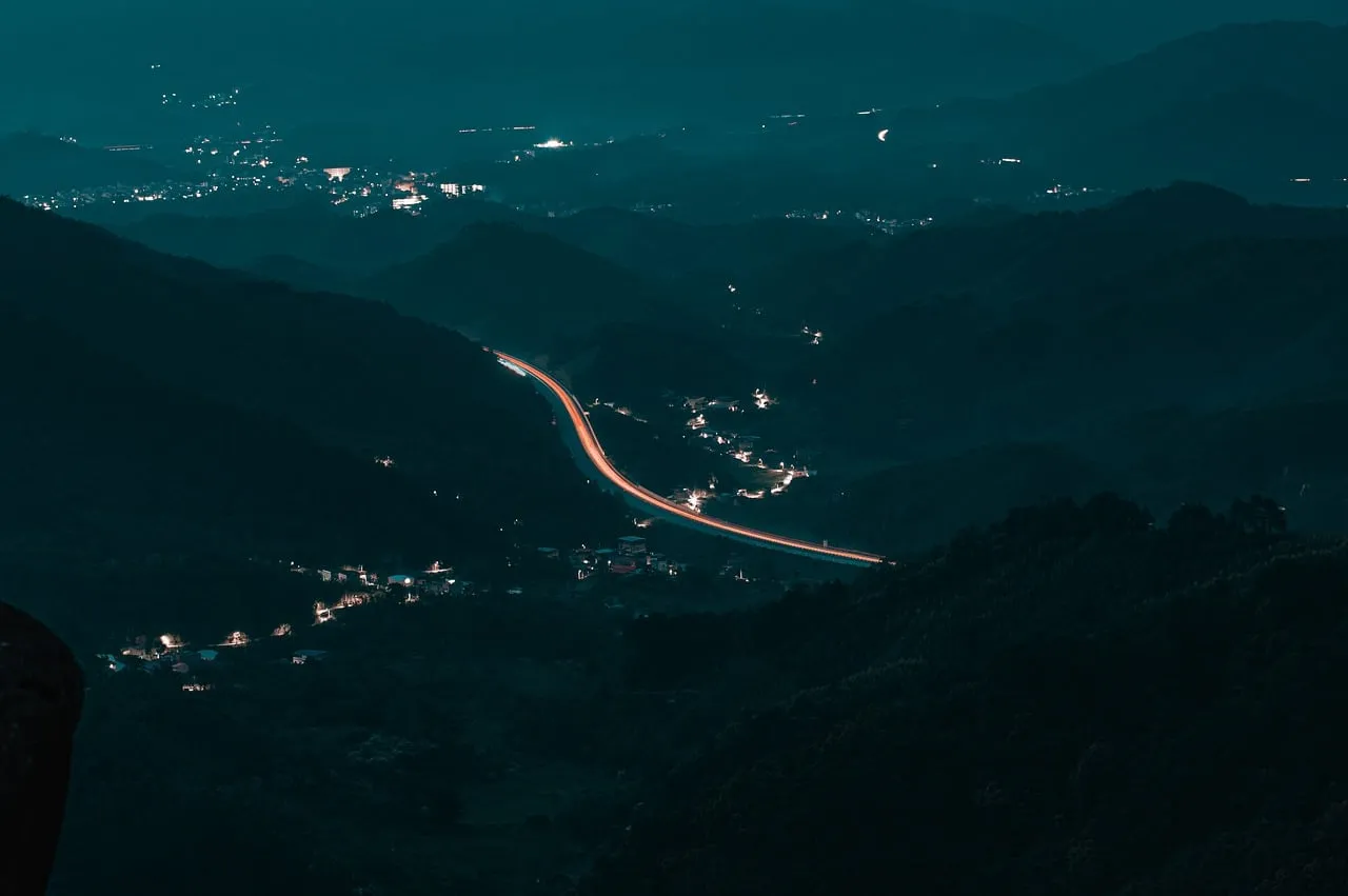 Enchanting Night Landscape: Serpentine Highway Illuminates Mountainous Terrain