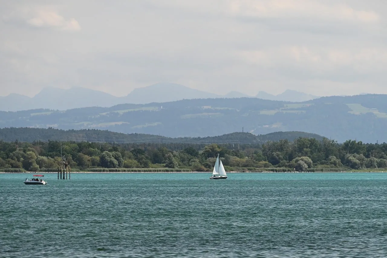 Serene Lake Constance: Sailboat Gliding Amidst Majestic Mountains