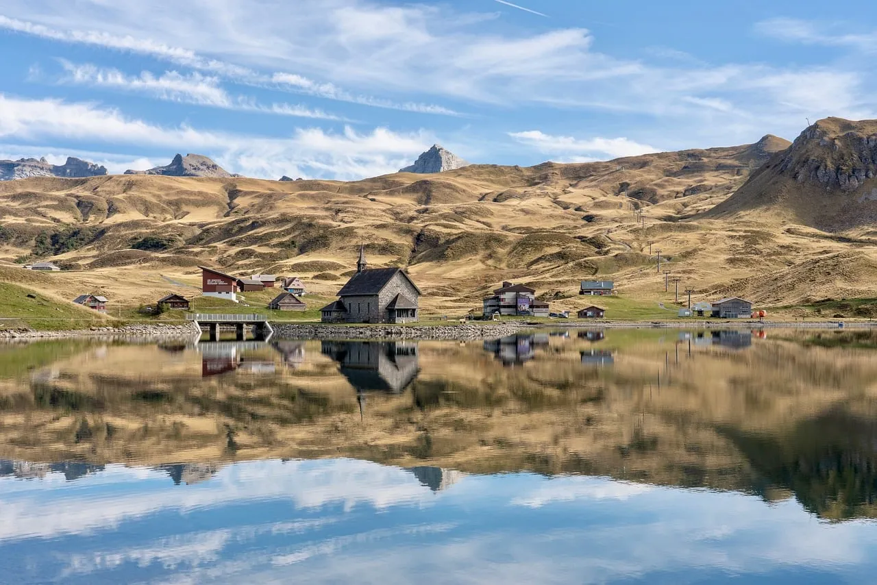 Breathtaking Alpine Panorama: Serene Lake Reflects Mountain Village