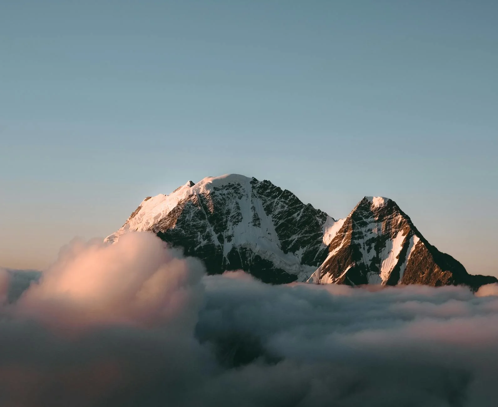 Majestic Snow-Capped Peaks Above Clouds at Sunset