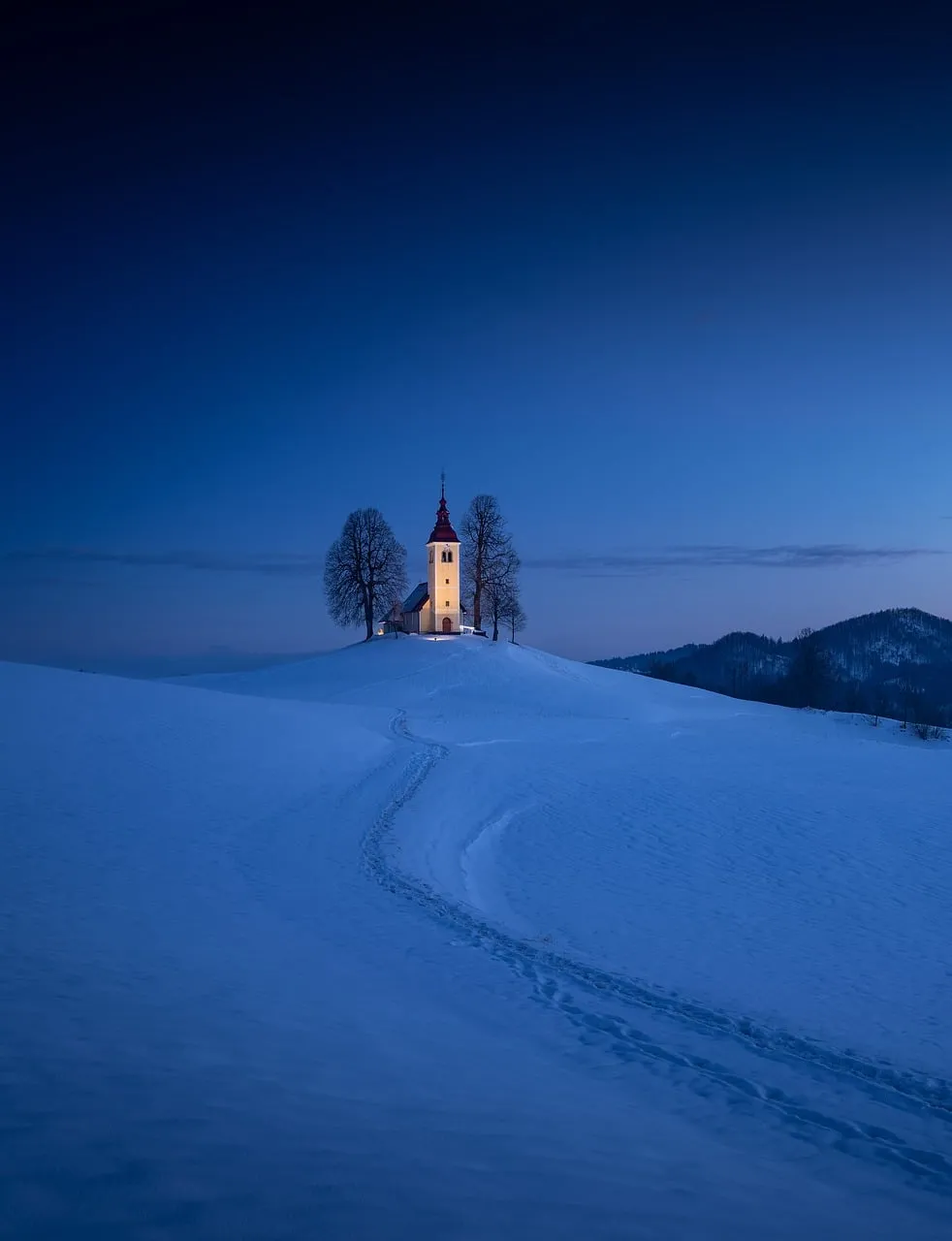 Enchanting Winter Wonderland: Solitary Church Under Blue Hour Sky