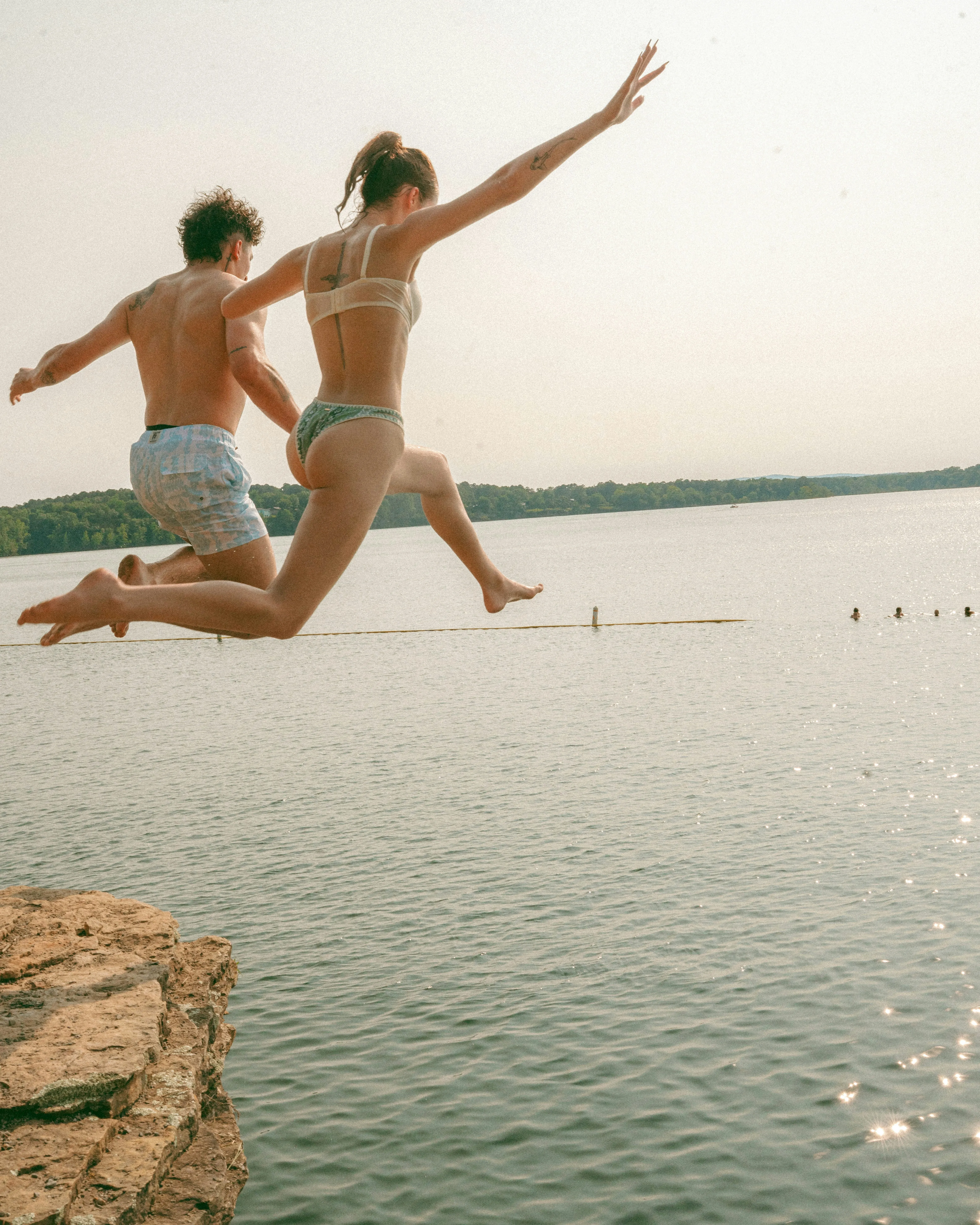 Thrilling Cliff Jump: Friends Dive into Summer Lake Adventure