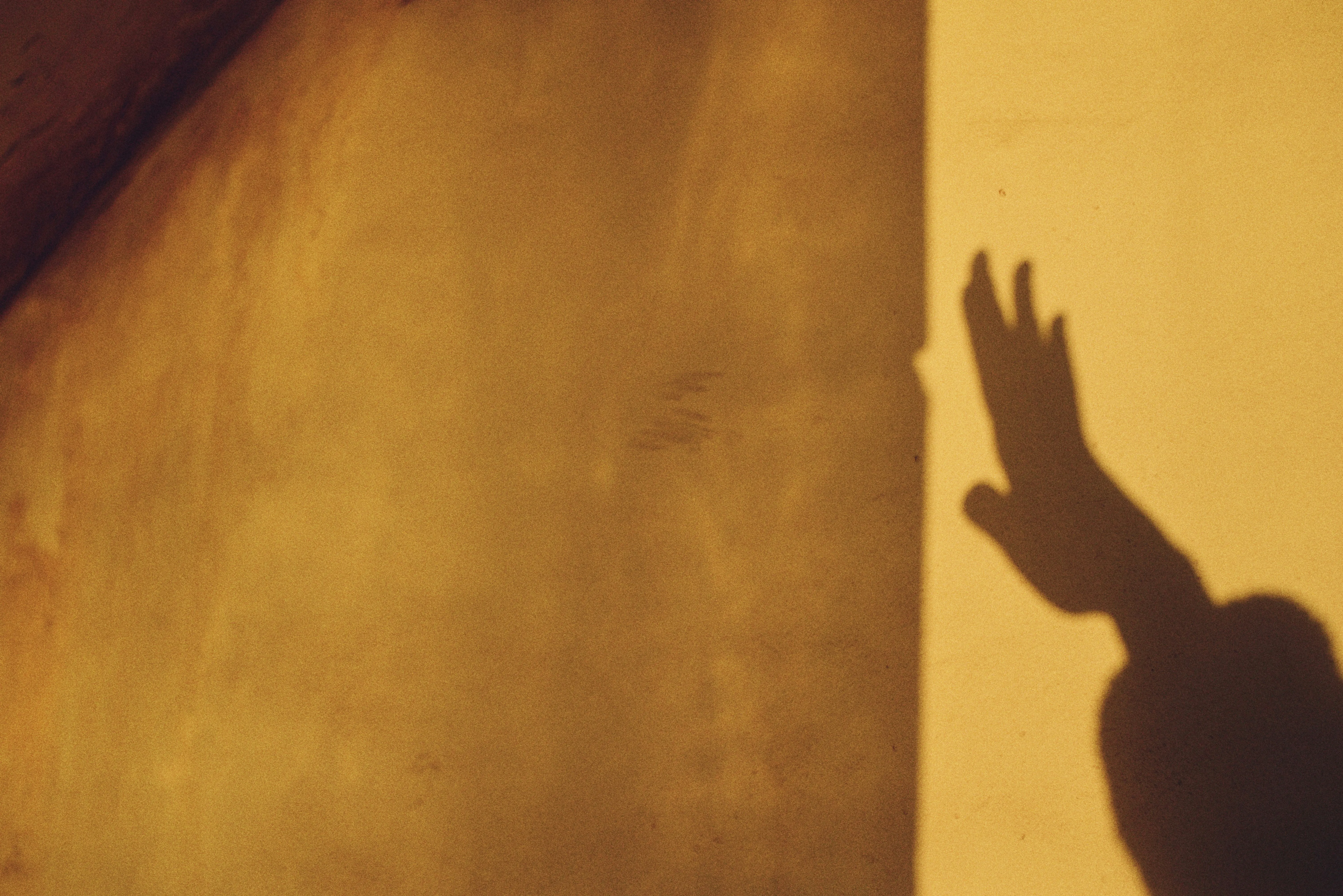 Dramatic Hand Shadow on Textured Wall at Sunset