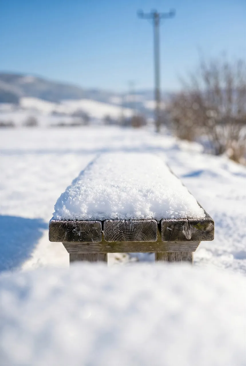 Serene Winter Day: Snow-Covered Bench in Idyllic Countryside