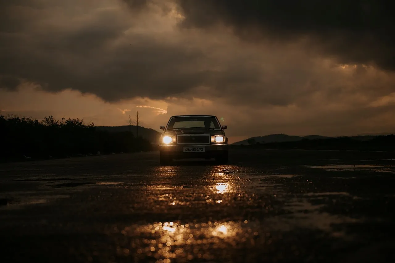 Dramatic Sunset Retro Ride: Classic Car on Wet Road