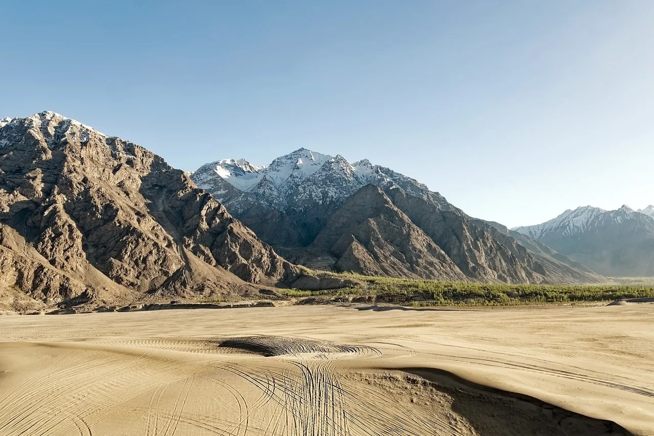 Majestic Snow-Capped Peaks Loom Over Arid Desert Sands