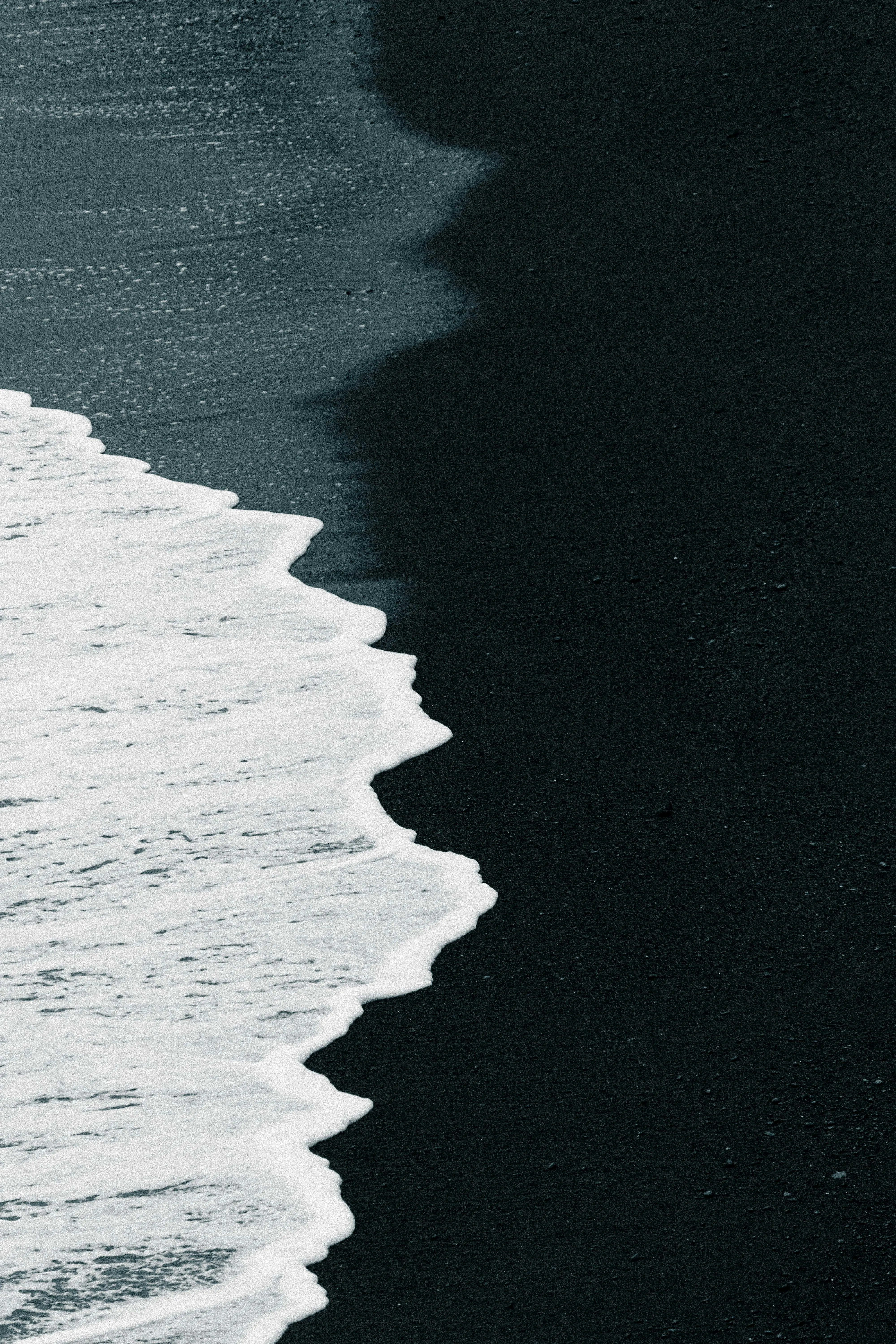 Dramatic Contrast: White Waves on Black Sand Beach