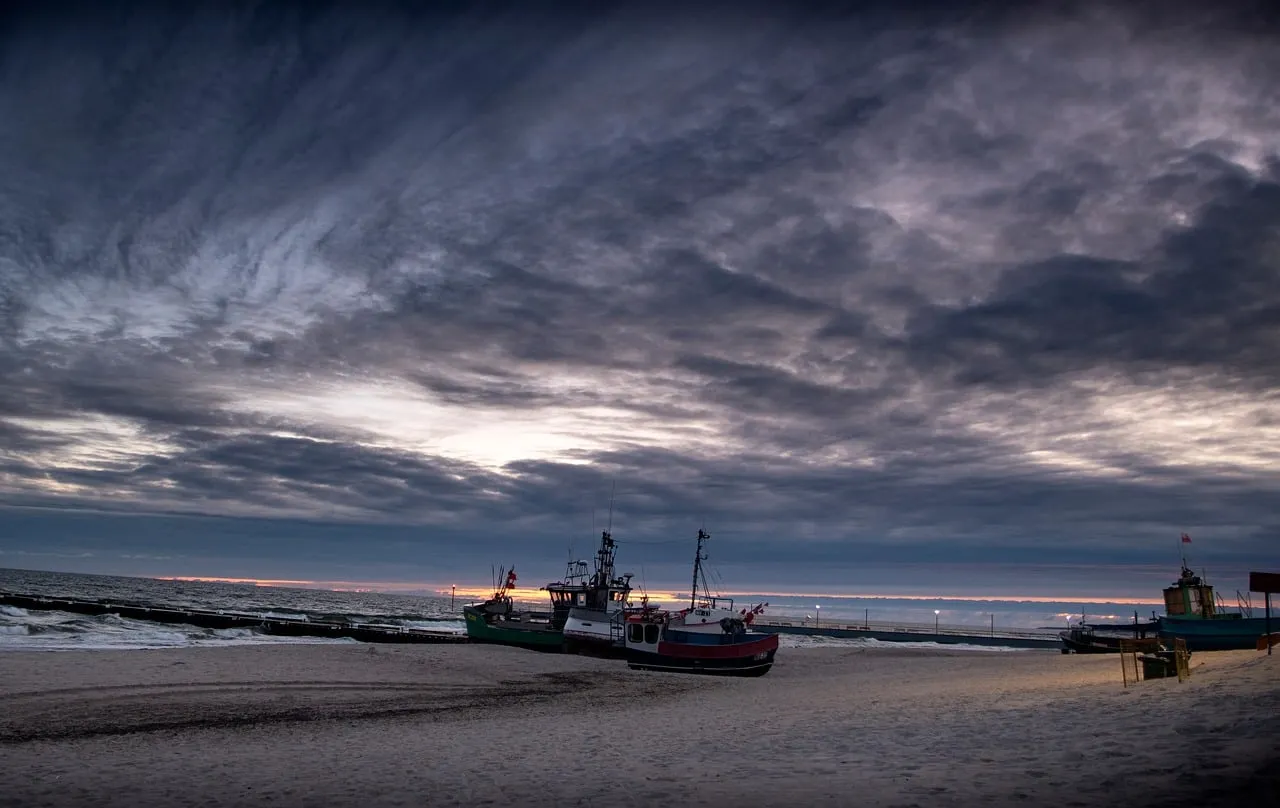 Dramatic Coastal Sunset: Fishing Boats on the Shore