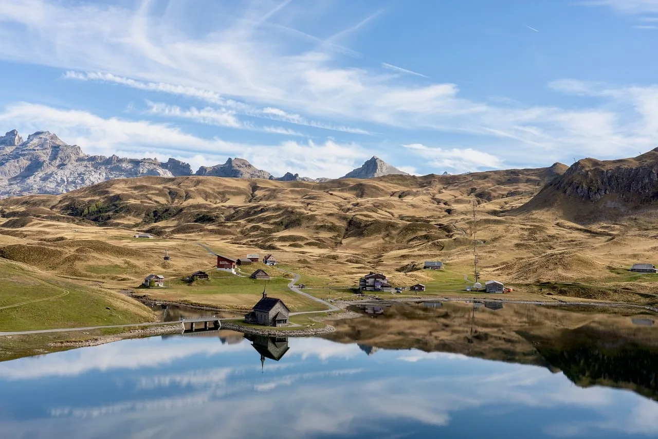 Serene Alpine Reflection: Mountain Lake & Village Panorama