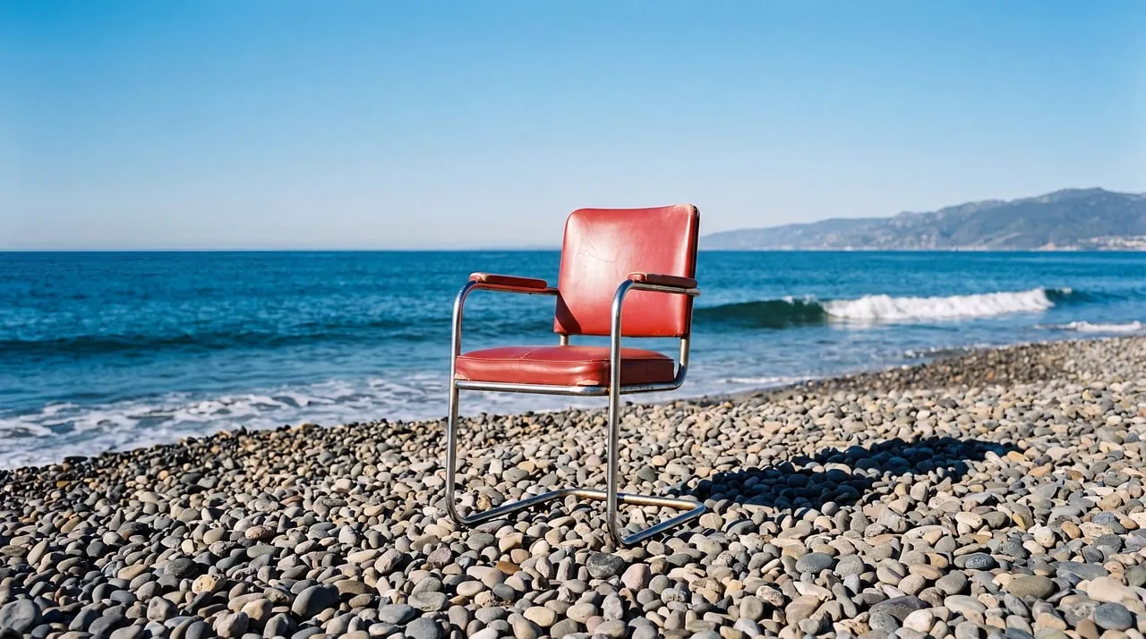 Serene Solitude: Red Chair on a Tranquil Pebble Beach