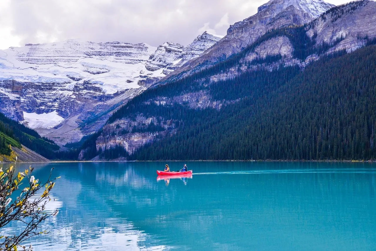 Iconic Red Canoe on Turquoise Lake Louise Amidst Snow-Capped Rockies