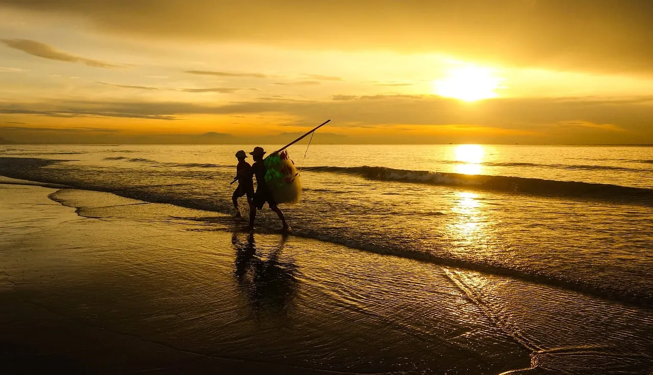 Golden Dawn: Fishermen's Silhouettes Against a Radiant Sunrise Sea