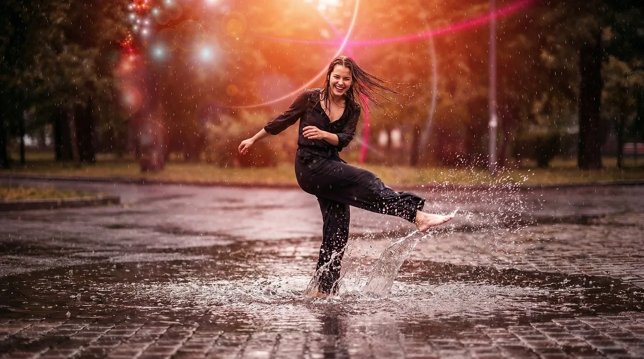 Joyful Woman Splashing in Puddles at Sunset