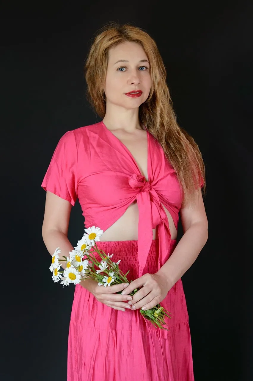 Radiant Woman in Pink Dress with Daisy Bouquet on Black Background